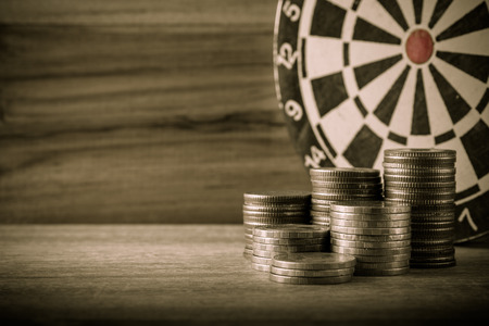 Coin with dart board on the wood table in retro and vintage style background in finance,success and target conceptの写真素材