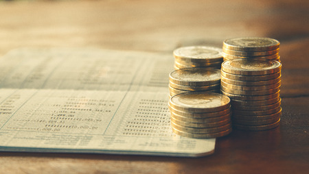 row of coins  and account book on the table in banking and finance conceptの写真素材