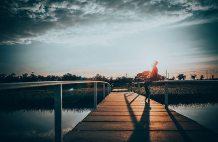girl on a bridge on the sunset in sad and lonely conceptの写真素材