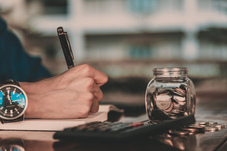 Close up of people hand work calculator and money,coins in finance banking and  saving conceptの写真素材