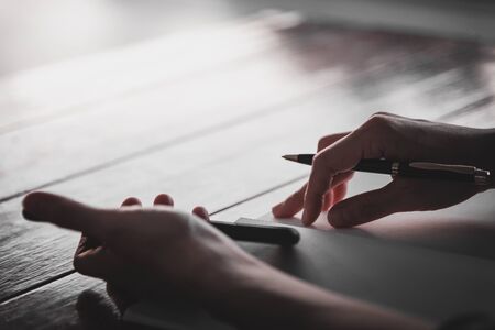 People writing on notebook and work with calculator and laptop on wooden tableの写真素材