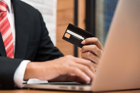 businessman holding credit card and using laptop in his office in payment,finance and banking conceptの写真素材