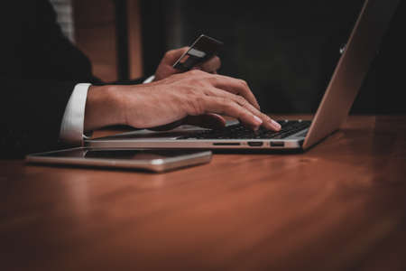 businessman holding credit card and using laptop in his office in payment,finance and banking conceptの写真素材
