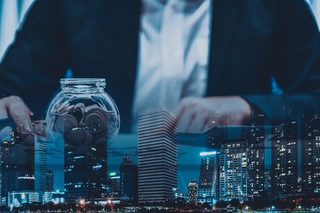 double exposure of businessman working with coins and city  in finance and business conceptの写真素材