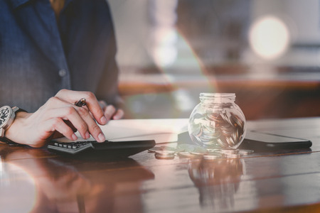 Close up of people hand work calculator and money,coins in finance banking and saving conceptの写真素材