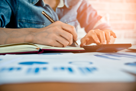 Business women work with calculator and laptop,pen and notebook on the wooden tableの写真素材