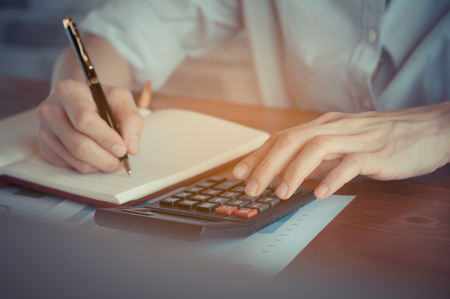 Business women work with calculator and laptop,pen and notebook on the wooden tableの写真素材