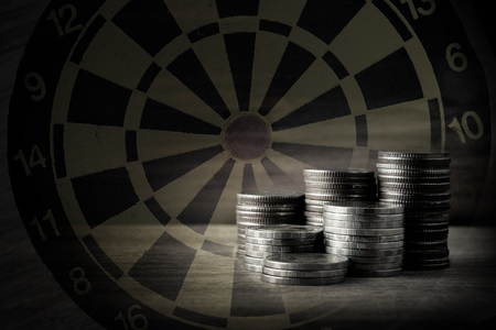 Coin with dart board on the wood table in retro and vintage style background in finance,success and target conceptの写真素材