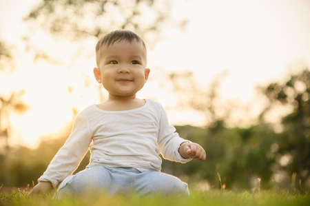 Happy child,kid or boy sitting on the ground in the outdoor park.の写真素材