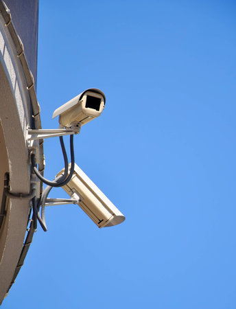 Two CCTV security cameras and blue skyの写真素材