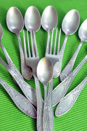 Silver forcs and spoons on green background