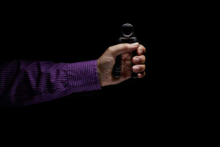 Hand gripping a hand strenghener under tension. Metaphor for stress or pressureの写真素材
