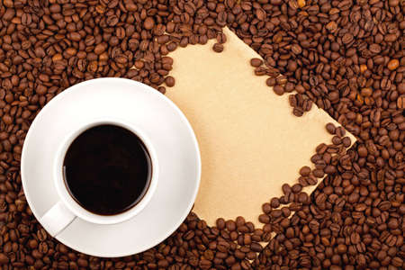 White cup full of coffee placed on coffee crops and hand-made paper for copy-spaceの写真素材
