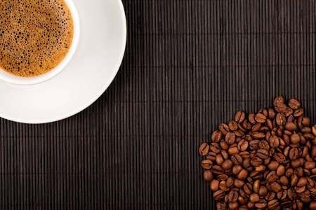 White coffee cup and crops on bamboo coaster. Place for text.の写真素材