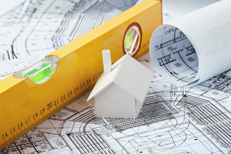 Small simple white model house on prints with a yellow leveler