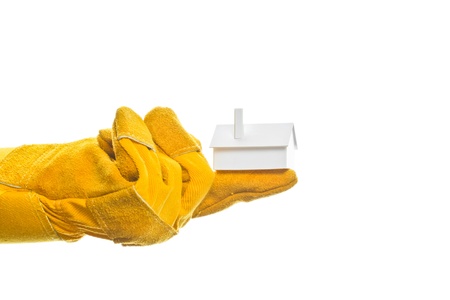 Worker s hand in a safety glove holding a model house on his index finger, isolated on white の写真素材