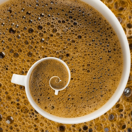 White mug full of coffee with foam in a swirlの写真素材