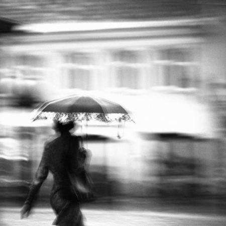 Woman in a rain walking with umbrella. Unrecognizable person in motion blur.の写真素材