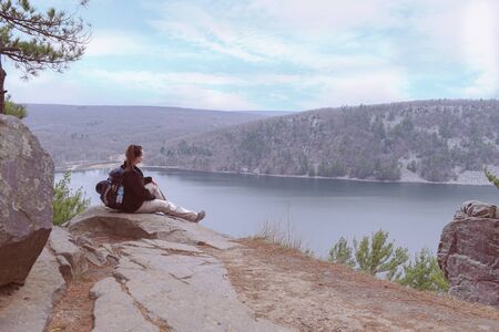 young lady sits on the rocks and looking for a new pathの写真素材
