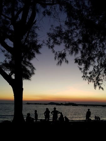 Silhouette of peoele and tree on the beach with a beautiful sunset in backgroundの写真素材