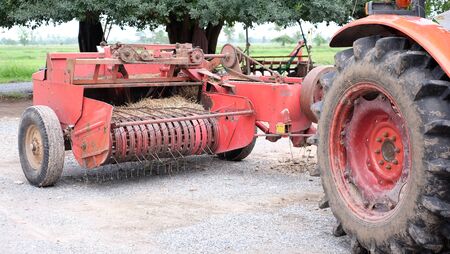 Closeup shot of red vintage tractor and  agricultural vehicle / making hay balesの写真素材
