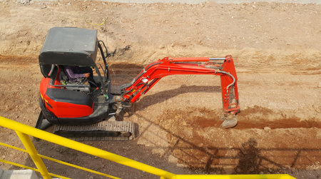 Small backhoe is working digging down the ground to installation drain pipe the water