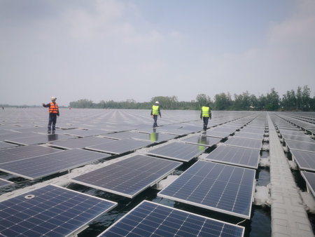 A large number of solar panels are installed on gray plastic pontoons over a body of...