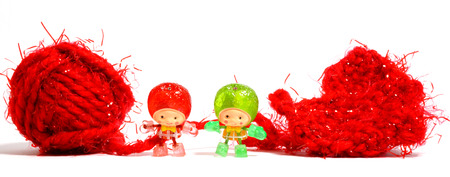 Cute little dolls and red wool ball isolated on white background.の写真素材