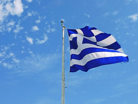 Image of greece flag flying at wind over blue sky