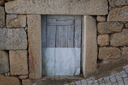 Old wooden door in a stone wall of an old house in Spainの写真素材