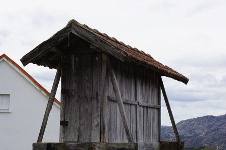 Old wooden well on a background of the village and cloudy sky.の写真素材