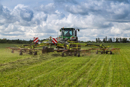 Russia, Leningrad Region - June, 2019: Powerful tractor brand JOHN DEERE and brand Krone rotary rakes at the exhibitionのeditorial素材
