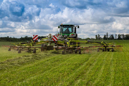 Russia, Leningrad Region - June, 2019: Powerful tractor brand JOHN DEERE and brand Krone rotary rakes at the exhibitionのeditorial素材