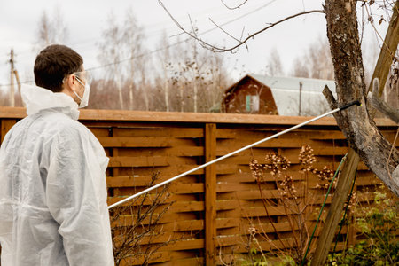 Using chemicals in the garden orchard gardener applying an insecticide a fertilizer to his fruit...