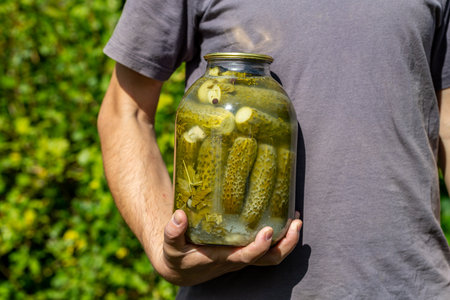 hands hold a jar of marinated cucumbersの写真素材