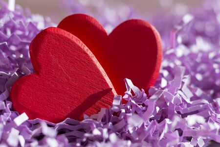 Two red hearts in purple paper tinselの写真素材