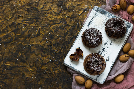 Chocolate muffins with pecans under chocolate ganache and coconut chips