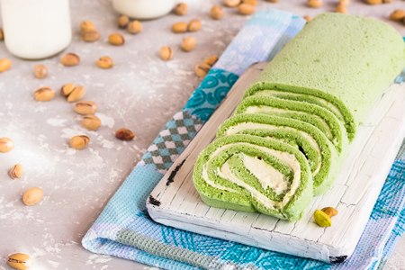 Biscuit pistachio roulette on white rustic boardの写真素材