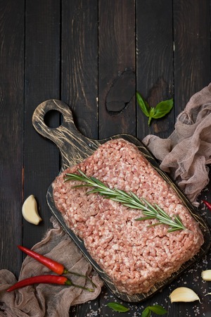 Raw ground meat with fresh herbs and pink Himalayan salt on a dark backgroundの写真素材