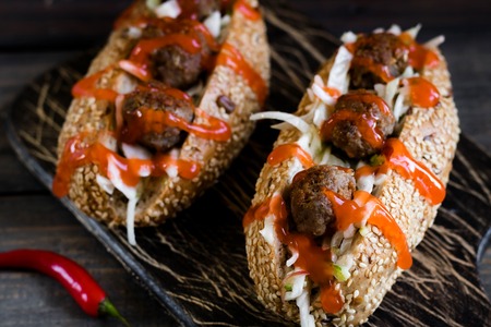 Spicy hot dog with meatballs with apple and cabbage garnish on a dark backgroundの写真素材