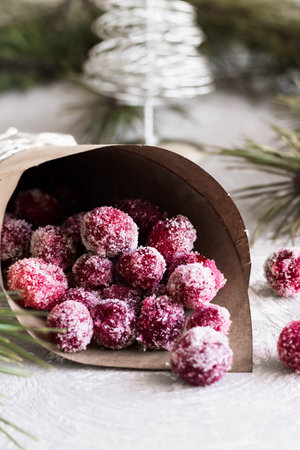Candied cranberries in a crafting bag on the background of fir cones