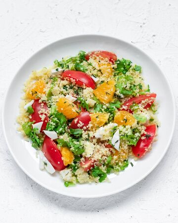 Healthy and simple food, light summer lunch, fragrant salad with couscous and oranges on a light backgroundの写真素材