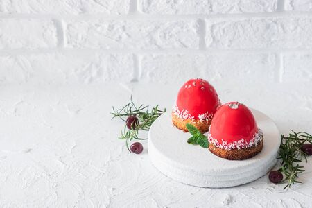 Fashionable mousse cake with mirror glaze and cherry filling on a pillow of coconut cookies with coconut flakes. Modern dessert.の写真素材