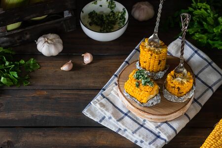 Baked corn with spiced butter on a rustic wooden background. Food for the holidays and barbecue. Autumn harvest.の写真素材
