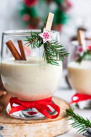 A traditional eggnog Christmas drink in a glass goblet decorated with New Year clothespin. Non-alcoholic option. Atmospheric photos.の写真素材