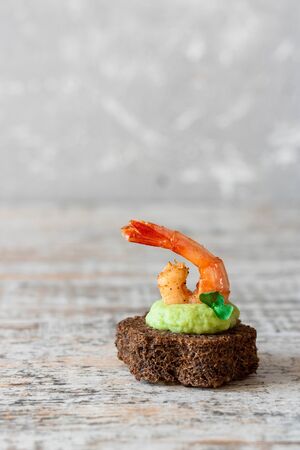 Canapes with avocado and garlic shrimp on brown bread. Simple and easy snack for parties and banquets. Comfortable food.の写真素材
