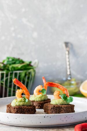Canapes with avocado and garlic shrimp on brown bread. Simple and easy snack for parties and banquets. Comfortable food.の写真素材