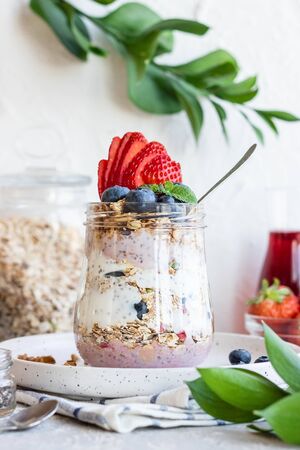 Yogurt pudding with chia seeds, homemade granola and fresh berries in a glass jar. Light snack. Healthy breakfast option.の写真素材