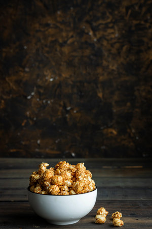 Salted caramel popcorn in a white plate. Dark wood backgroundの写真素材
