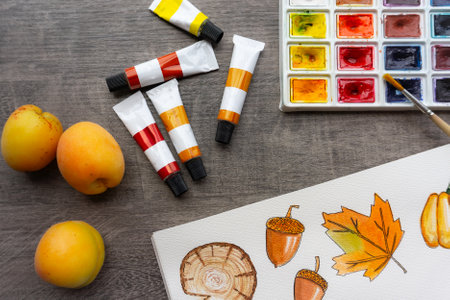 Tubes of paint on a wooden table, palette, autumn watercolor drawing, bright compositionの写真素材